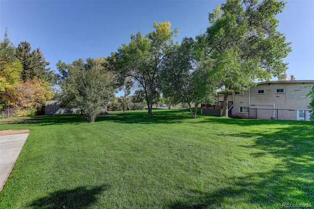 a view of a house with a big yard and large trees