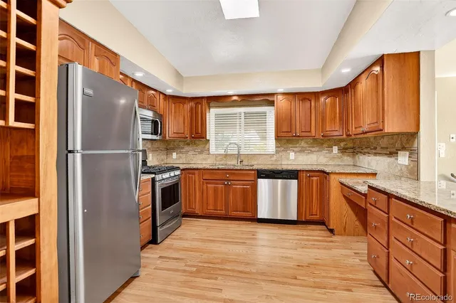 a kitchen with stainless steel appliances granite countertop a refrigerator and a stove top oven