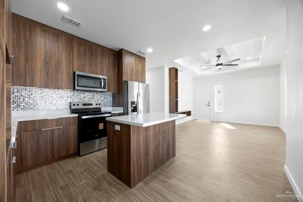 a kitchen with stainless steel appliances granite countertop a stove a sink dishwasher and a refrigerator with wooden floor