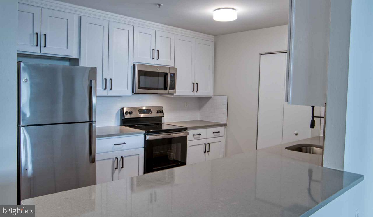 a kitchen with stainless steel appliances granite countertop a refrigerator stove and white cabinets