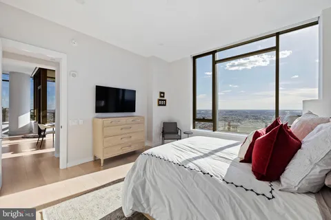 a large bedroom with a bed and a flat tv screen next to a window