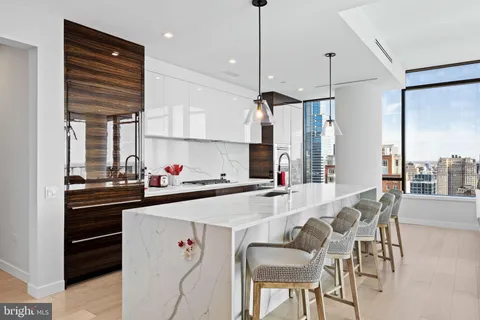 a kitchen with stainless steel appliances a sink a stove and chairs