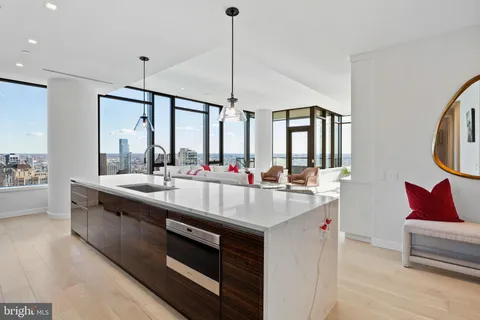 a kitchen with stainless steel appliances granite countertop a sink a counter top space and living room view