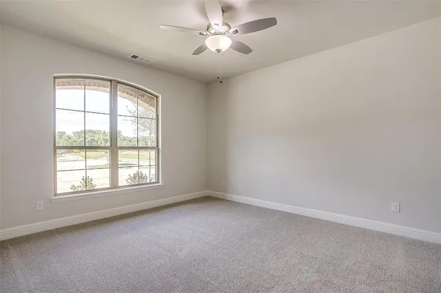 an empty room with a window and a fan