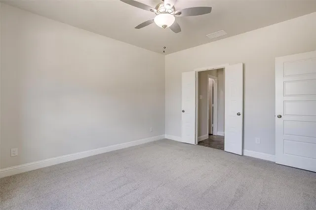 an empty room with closet and a chandelier fan