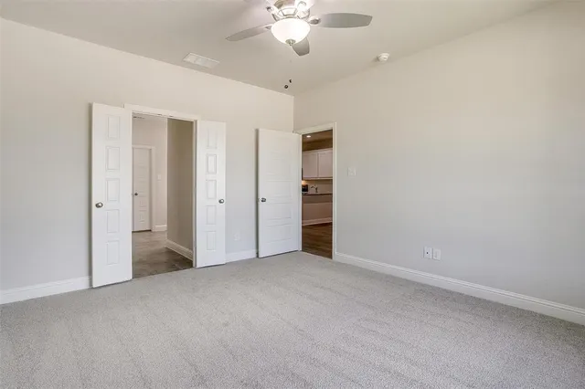 an empty room with closet and a ceiling fan