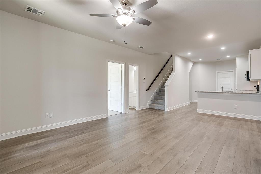 6819 Robert Reed Drive Arlington, TX 76001 - Photo 4 of 32 a view of an empty room with wooden floor a ceiling fan and windows