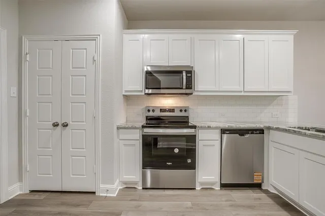 a kitchen with white cabinets and stainless steel appliances