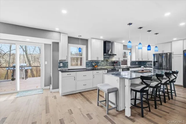 a kitchen with stainless steel appliances kitchen island granite countertop a stove a sink a refrigerator with a dining table and chairs