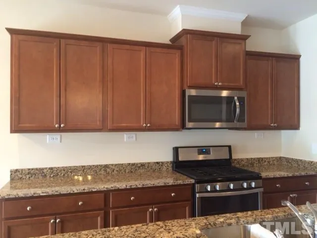 a kitchen with granite countertop stainless steel appliances a stove a microwave and cabinets