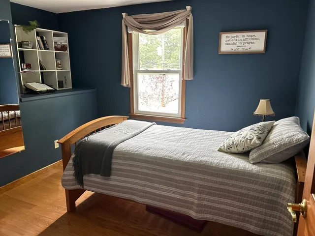 a bedroom with a bed and a lamp on dresser