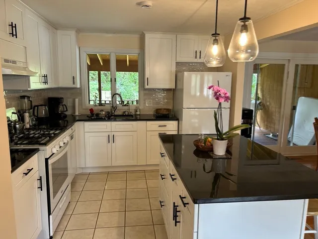 a kitchen with a sink dishwasher a stove a microwave oven and a dining table with wooden floor