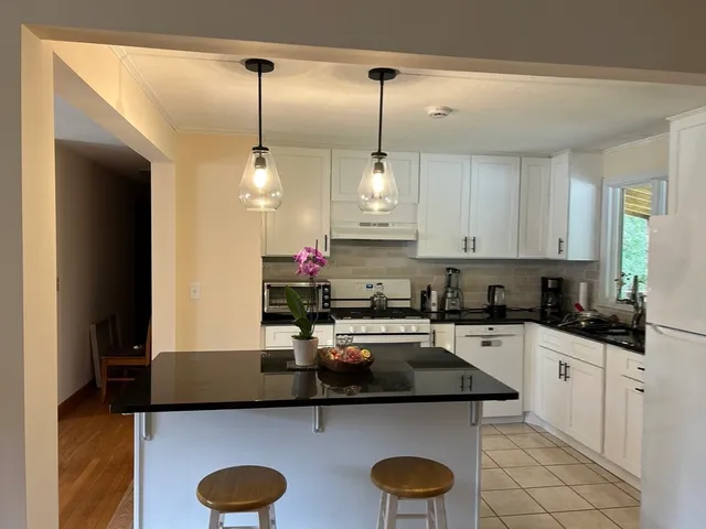 a kitchen with stainless steel appliances granite countertop a sink a stove and a wooden floors