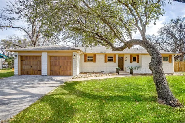 a front view of a house with a garden and trees