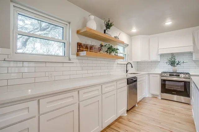 a kitchen with granite countertop white cabinets a sink a window and stainless steel appliances