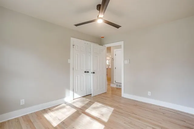 a view of an empty room and wooden floor chandelier fan