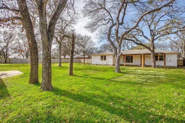 a view of a house with a big yard and large trees