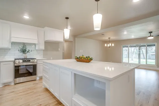 a kitchen with a stove a sink a center island and wooden floor