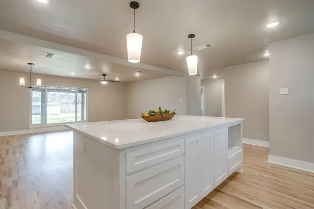 a kitchen with a sink chandelier and wooden floor