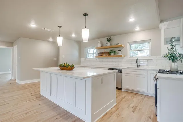 a kitchen with kitchen island granite countertop a sink a counter space appliances and cabinets