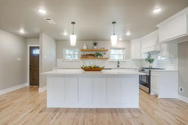 a kitchen with stainless steel appliances a refrigerator and a stove top oven