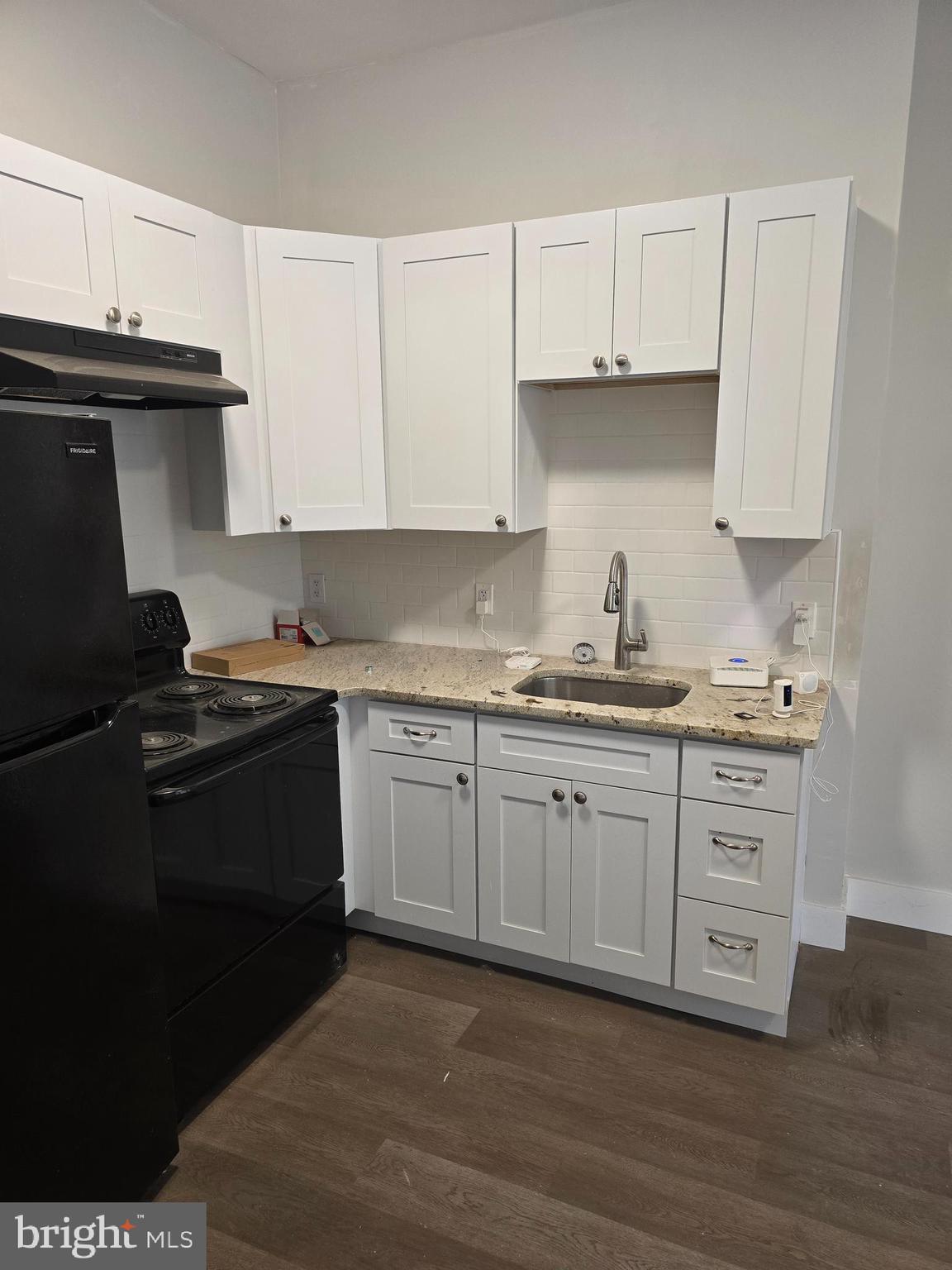 1321 West Wingohocking Street, Unit 1 Philadelphia, PA 19140 - Photo 7 of 19 a kitchen with granite countertop white cabinets and black appliances