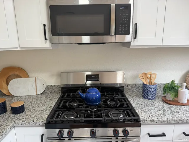 a kitchen with granite countertop a sink stove and cabinets