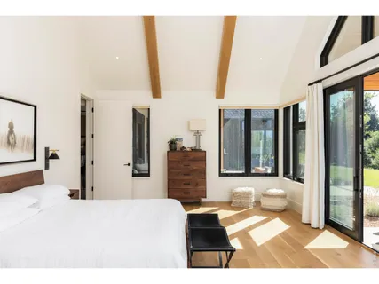 a bedroom with a bed and a large mirror next to a window