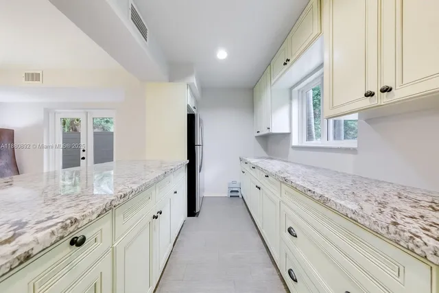 a large kitchen with granite countertop a sink and dishwasher with white cabinets