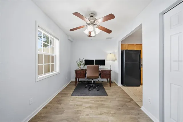 a dining room with wooden floor a chandelier fan a flat screen tv and a large window