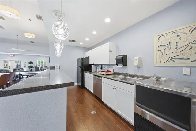 a large kitchen with stainless steel appliances granite countertop a sink dishwasher a stove and white cabinets with wooden floor