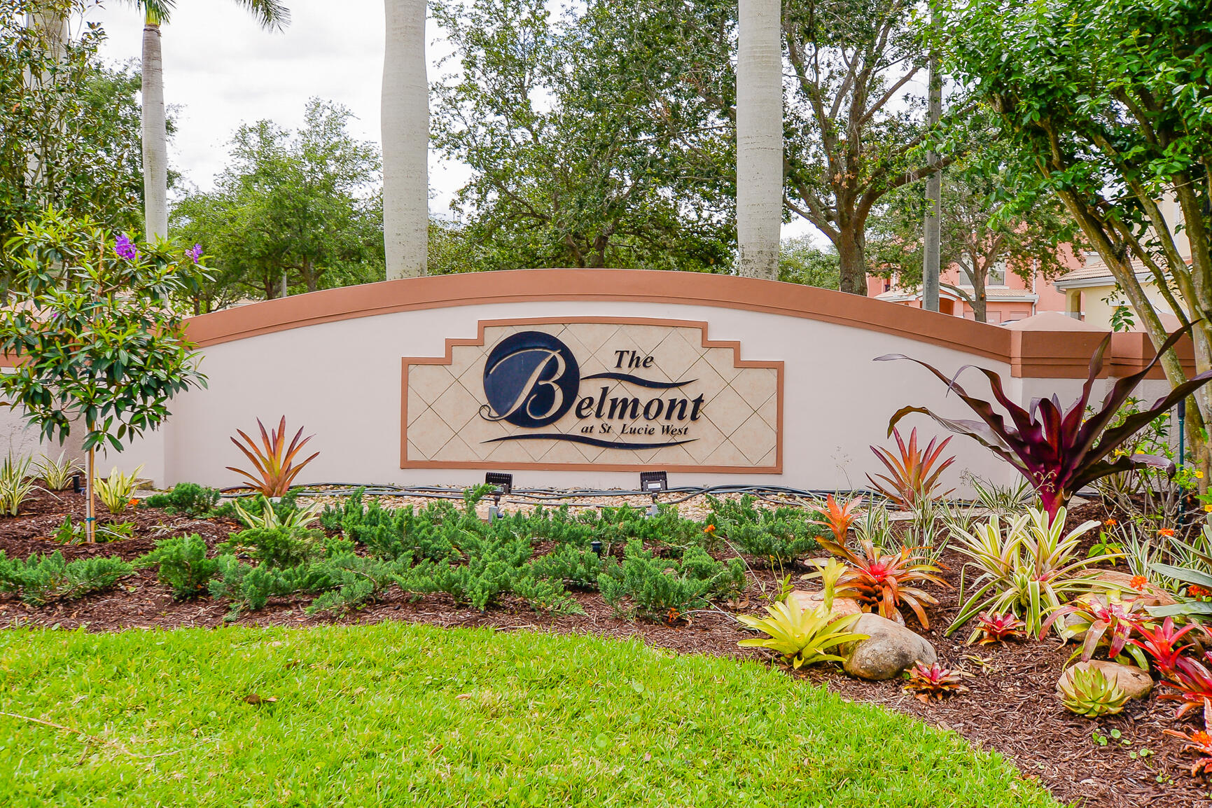 106 Southwest Peacock Boulevard, Unit 4204 Port St. Lucie, FL 34986 - Photo 47 of 47 a sign that is sitting on a brick wall with plants and large trees