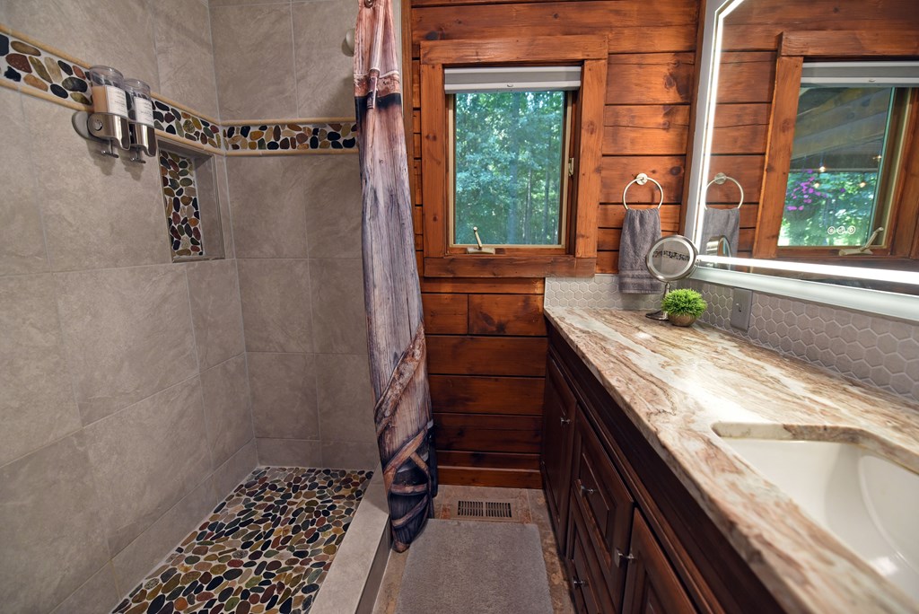 90 Log Cabin Road Blairsville, GA 30512 - Photo 27 of 45 a bathroom with a granite countertop sink and a shower