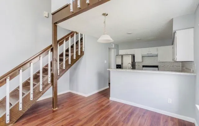 a view of staircase and kitchen with wooden floor