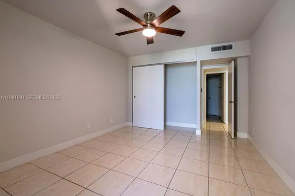 an empty room with chandelier fan and windows