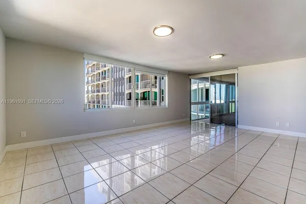 an empty room & kitchen view with windows