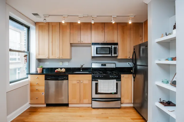a kitchen with stainless steel appliances a stove a refrigerator a sink and white cabinets