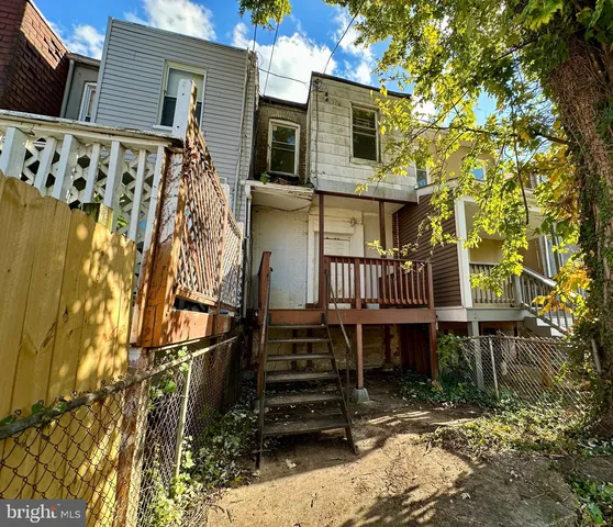 a view of a house with a wooden fence and a large tree