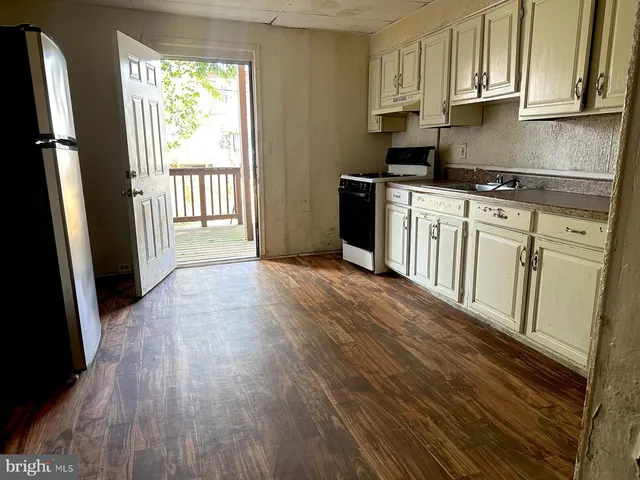 a kitchen with stainless steel appliances a stove a refrigerator a sink and wooden floors