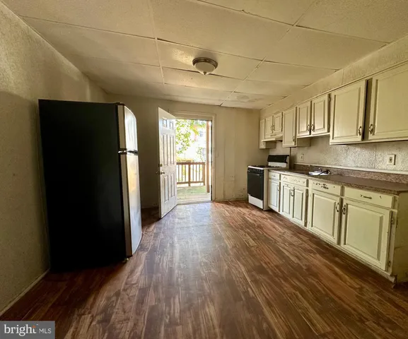 a kitchen with stainless steel appliances granite countertop a refrigerator a sink dishwasher a stove and white countertops with wooden floor