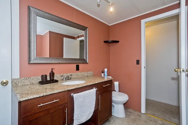 a bathroom with a granite countertop toilet sink and mirror