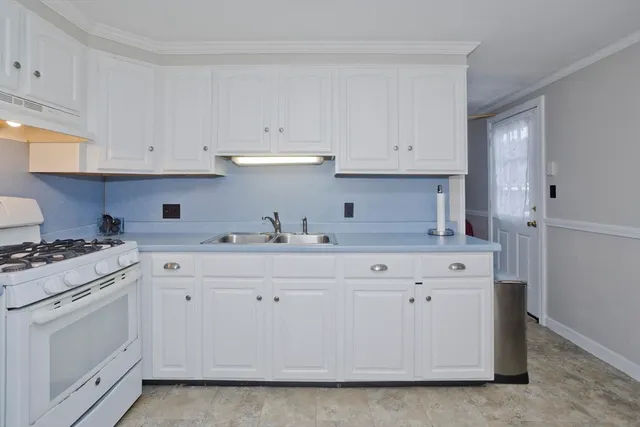 a kitchen with granite countertop white cabinets and white stainless steel appliances