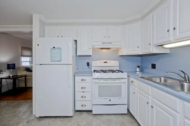 a kitchen with white cabinets and sink