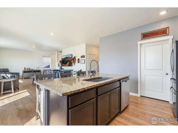 a kitchen with stainless steel appliances granite countertop a table chairs sink and cabinets