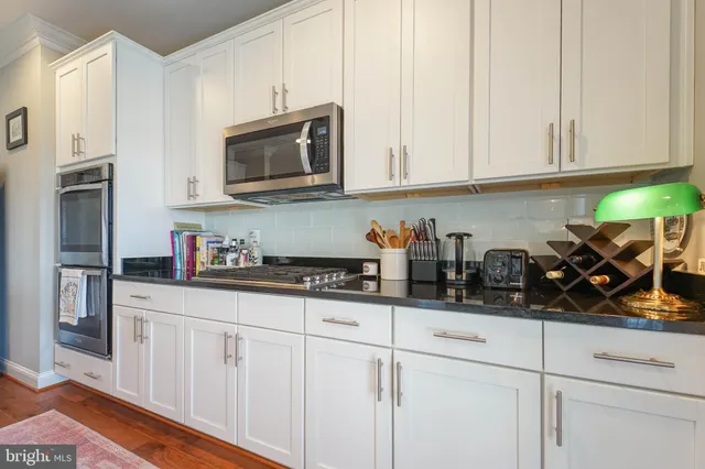 a kitchen with stainless steel appliances granite countertop white cabinets and a stove top oven