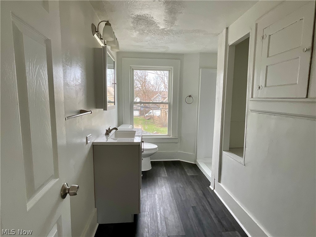 425 Spaulding Street Akron, OH 44310 - Photo 11 of 17 Bathroom featuring a stall shower, vanity, dark wood-style flooring, and a textured ceiling