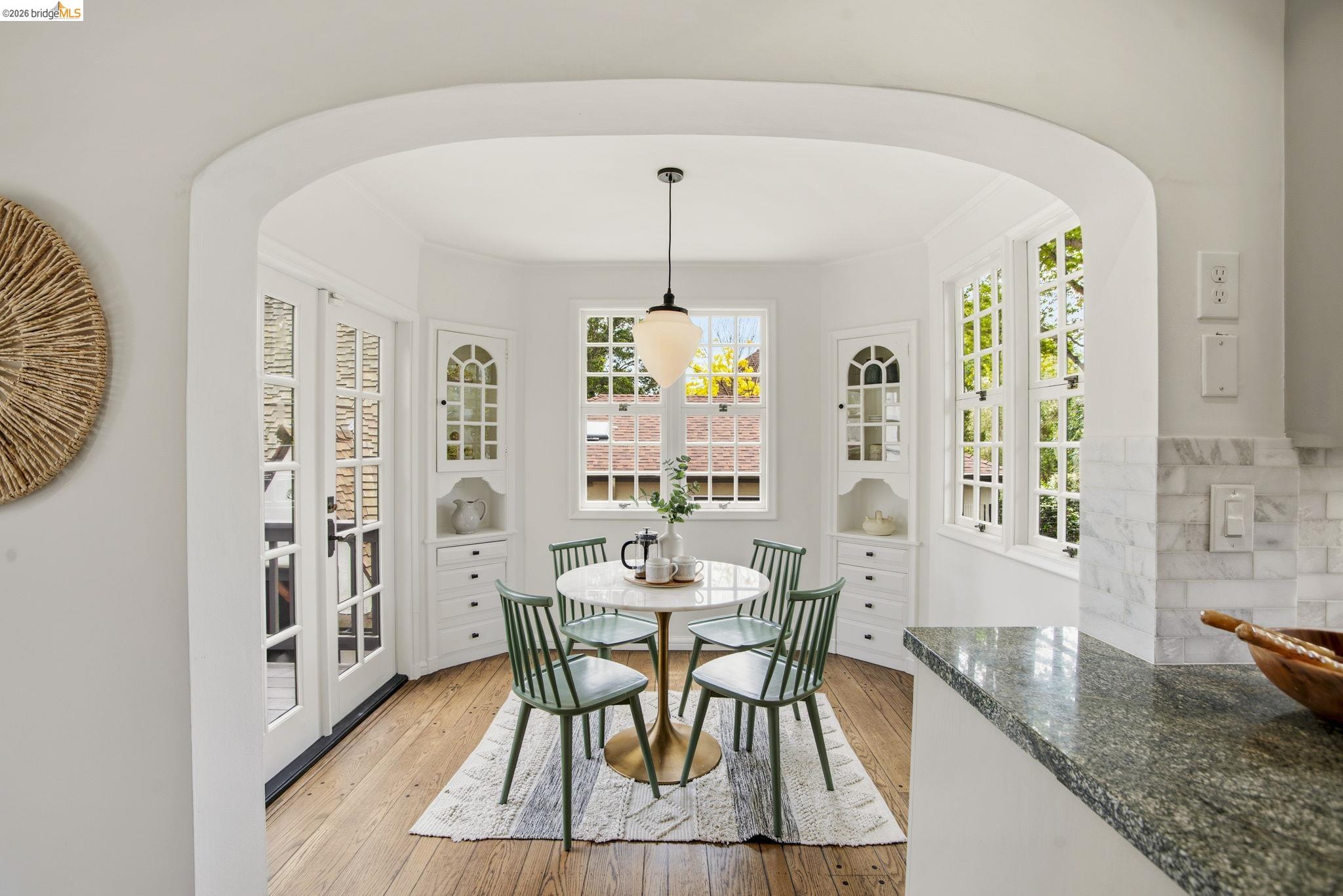 1087 Hubert Road Oakland, CA 94610 - Photo 17 of 67 Arched entryway opening to a dining area featuring wood-finish flooring, built-in cabinetry, multiple windows, and a pendant light fixture