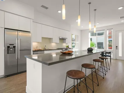 a kitchen with stainless steel appliances granite countertop a sink a stove a refrigerator cabinets and chairs