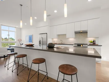 a kitchen with stainless steel appliances granite countertop a sink a stove a refrigerator a center island and chairs in it