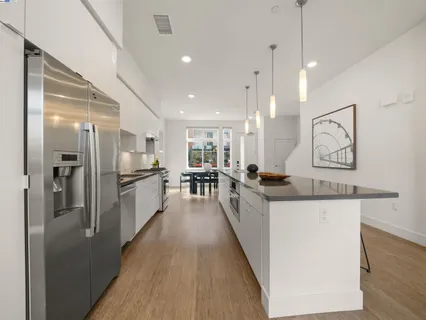 a large kitchen with stainless steel appliances kitchen island a large counter top and wooden floors